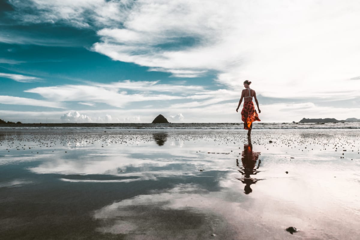 Persona caminando en una playa al atardecer